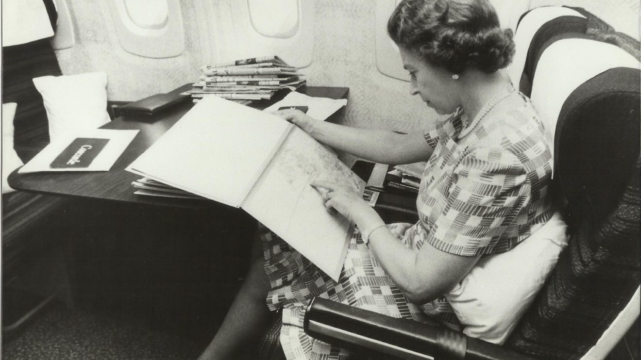 Isabel II a bordo del concorde en 1977 consultando un mapa con la ruta.