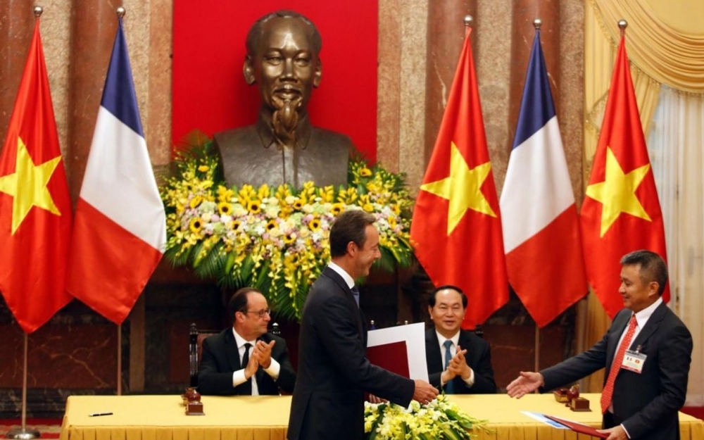 Los presidentes de Airbus (izquierda) y Vietnam Airlines se dan la mano tras la firma del acuerdo entre ambas empresas en presencia de los presidentes de Francia y Vietnam.