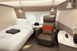 Cabina de primera clase de Singapore Airlines con cama y asientos separados.